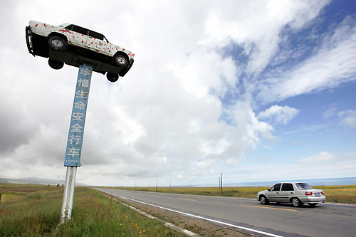A car (L) destroyed in a traffic accident is displayed by the Qinghai-Tibet highway to remind drivers to drive safely in Huangyuan County, northwestern China's Qinghai province, August 18, 2006. The sign reads "Cherish your life, drive carefully". 