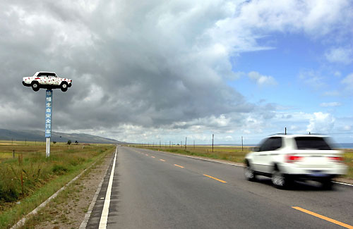 A car (L) destroyed in a traffic accident is displayed by the Qinghai-Tibet highway to remind drivers to drive safely in Huangyuan County, northwestern China's Qinghai province, August 18, 2006. The sign reads "Cherish your life, drive carefully". 