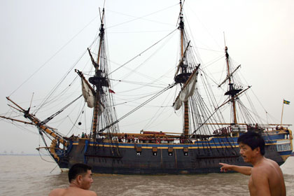 A man points at a replica of the 18th century Swedish merchant ship Gotheborg at Baoshan Wharf in Shanghai August 28, 2006. 