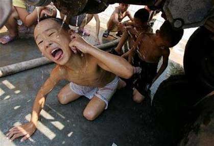 A child drinks water under a fire engine, which is used to transport water to drought-suffering residents, in southwest China's Chongqing September 1, 2006. China will invest billions of dollars over the next 10 years to provide drinking water for 300 million rural residents who face shortages or are without access to clean water, local media reported on Tuesday. [Reuters]
