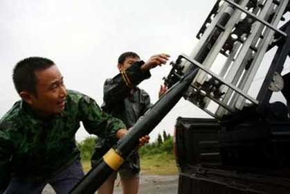 The staff of Suining Weather Modification Office load a projectile during an artificial rain enhancement operation in Suining, southwest China's Sichuan province, September 4, 2006. The projectile was fired in an attempt to increase rainfall when it was raining. [Reuters]