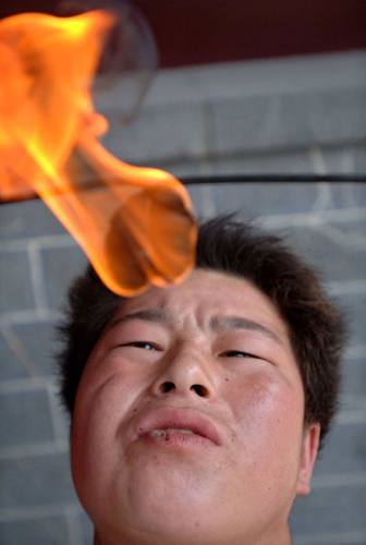 Liu Gang tries to extinguish a torch by putting it into his mouth during a stunt performance at a park in Hefei, east China's Anhui province October 2, 2006. China is celebrating a week-long National Day holiday, which started on Sunday, a time when millions of Chinese travel to major cities to enjoy cultural attractions or return home to visit relatives and friends. [Reuters]
