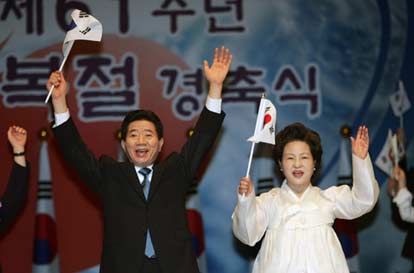 South Korea's President Roh Moo-hyun (L) and his wife Kwon Yang-sook wave the national flag at a ceremony, marking the end of World War Two and Japanese rule 61 years ago, in Seoul August 15, 2006. 