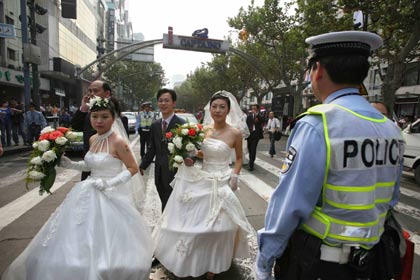 Some of 70 couples stand in a queue during a mass wedding event in Shanghai October 5, 2006. Some 2,000 couples registered their marriage this Monday in Shanghai, according to statistics, and there is an estimated 30,000 couples to hold their weddings during the seven-day holiday period or the 'Golden Week' holiday, Xinhua news agency said.
