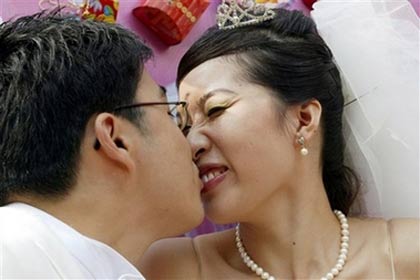 A Chinese newlyweds celebrate during the mass wedding ceremony, one of National Day holiday's attractions for locals in Shanghai, October 5, 2006. China is on a week-long National Day holiday which runs from Oct. 1 to 7. [AP Photo] 