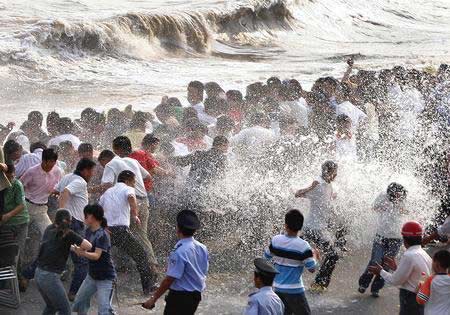 Spectators are scattered by strong tidal wave that hits the bank of Qiantangjiang River in Haining, East China's Zhejiang Province on October 9, 2006. The relative distance of the Moon from the Earth affects tide heights, said scientists, the best tide viewing time of the Qiantangjiang River falls on Monday this year. [newsphoto]
