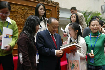 Foreign Minister Li Zhaoxing signs a book when receiving a group of students visiting the ministry on Saturday.
