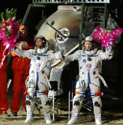 Astronauts Fei Junlong and Nie Haisheng wave to wellwishers after getting out of the return module of the Shenzhou VI spacecaft at the main landing field in Central Inner Mongolia Autonomous Region Monday morning October 17, 2005. The module landed 4:33 A.M. after a five-day flight. [Xinhua] 