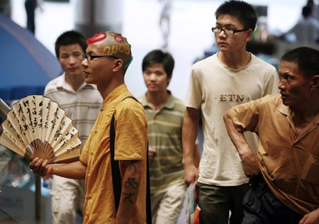 A man with 2008 Beijing Olympic Games icon tattoos and Olympic-themed hairstyle walks on a street in Hangzhou, east China's Zhejiang province August 31, 2006.