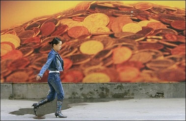 A woman walks past a construction site boarded off with a billboard showing currency coins in Beijing.(AFP/