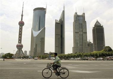 A worker rides bicycle past high-rise buildings Tuesday July 18, 2006 in Shanghai, China. Poverty, water shortages, environmental crises: Asia's booming giants, China and India, confront daunting challenges as they strive to keep their economies expanding fast enough to raise growing numbers of their 2.3 billion people out of poverty. (AP
