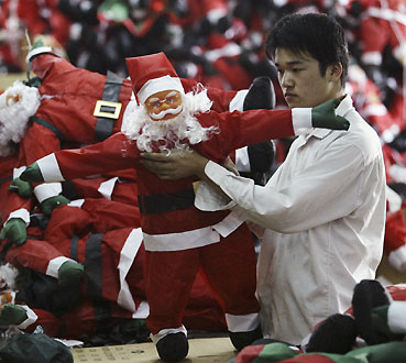 An employee works on a Santa Claus toy inside a factory producing Christmas decorations on the outskirts of Guangzhou, south China's Guangdong province, December 12, 2006. Picture taken December 12, 2006. 