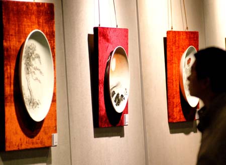 A visitor looks at the porcelain paintings on display at Chinese People Museum in Xiamen, East China's Fujian Province, December 30, 2006. The museum marked the opening on Saturday after 400 days' construction and had a display of paintings and sculptures. [newsphoto]
