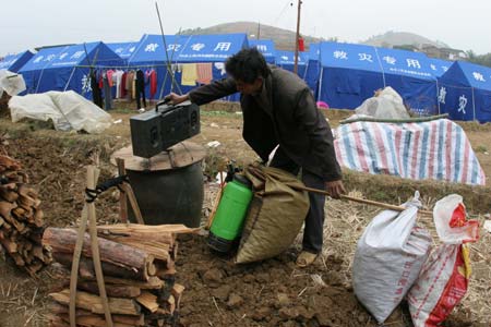 A man moves his belongings near the tents following a cave-in at Haijie Village, Nuotong Township, Guangxi Zhuang Autonomous Region, January 3,2007. The cave-in was caused by underground work on a nearby railway tunnel. Nobody was injured in the accident and some 257 villagers were evacuated to safe areas. [newsphoto]
