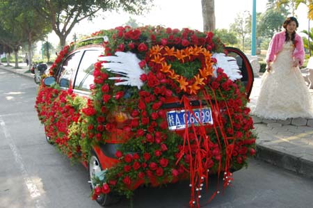 A bride poses for a picture with a car decorated with flowers in Nanjing, South China's Guangxi Zhuang Autonomous Region January 7, 2007. [newsphoto]