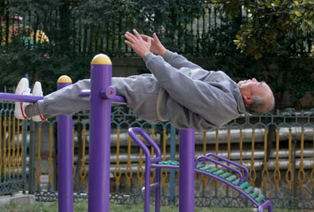 Wang Yongyou, 70, does exercise with the fitness equipment at a community in Huaibei City, East China's Anhui Province January 8, 2007. Wang was familiar with all the 45 sets of fitness equipments at the community and could make stunning performance, local residents said. [Wang Wen/Xinhua]
