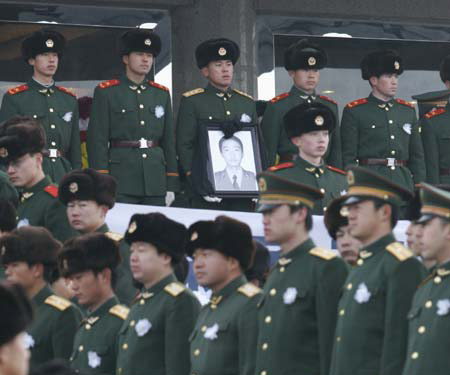 A Chinese soldier carries the picture of Huang Qiang, a 21-year-old policeman who died in a raid to a terrorist camp, during a memorial service in Urumqi, northwest China's Xinjiang Uygur Autonomous Region, January 9, 2007. Police have destroyed a terrorist camp in the mountains of Pamirs plateau in south Xinjiang, killing 18 terrorists and capturing 17 others.[newsphoto]