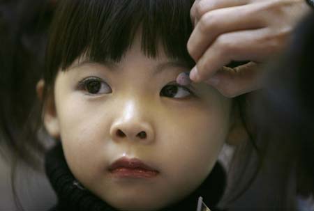 A participant in a child modelling competition receives make-up in Beijing January 13, 2007. The competition was held at the end of a model training course for about 200 children aged 4 to 16, during which they underwent physical training and received instruction on stagecraft and various kinds of dances such as step dance and ballet. 