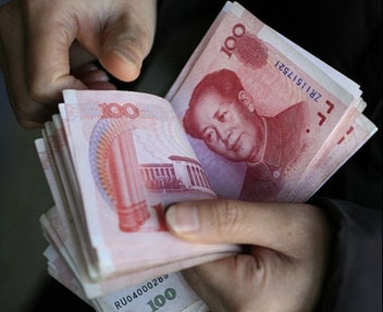 A man counts 100 yuan banknotes in Beijing. China's currency has hit a record post-revaluation high a day after Beijing announced a walloping rise in the country's full-year trade surplus.[AFP]