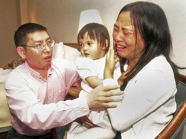 Shaoqiang He, left, comforts his wife, Qin Luo He, as she holds their daughter, Avita He, in their hotel room in Memphis, Tenn., May 12, 2004, after a judge ruled the couple were unfit to raise their 5-year-old daughter, Anna Mae, leaving her in the custody of the American foster family who raised her. [AP/file]
