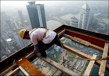 A Chinese construction worker goes about his work on a platform hanging out of a skyscraper building site in Wuhan. China's economic growth is expected to fall to 9.6 percent this year from 10.7 percent last year amid a mild slowdown in exports, the World Bank has said. [AFP]