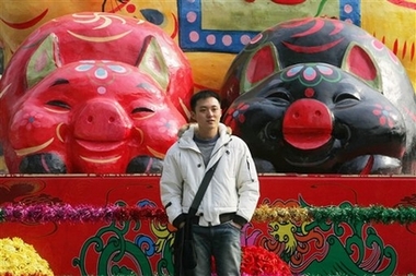 A man poses in front of pig decorations at a park in Beijing, Friday Feb. 16, 2007. 