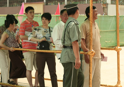 A security man talks with residents at the venue for a vote on demolishment and reconstruction of old buildings in Juixiaqiao Sub-district in Beijing, June 9, 2007. Local government and the real estate developer jointly organize the vote on Saturday to see if majority residents of over 5000 families accept the new compensation policy after failed attempts to reach an agreement through other ways. Both notary officials and supervisors are invited to monitor the vote that runs from 9 a.m. to 9 p.m. at six ballot booths. [Sun Yuqing/www.chinadaily.com.cn]