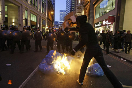 An anti-G20 demonstrator throws a box at riot police near the Bank of ...