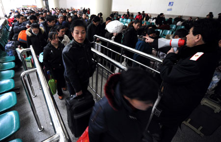 A raiway staff member uses a megapho to give orders as passengers wait to take trains back to work at the Lanzhou Railway Station, Northwest China's Gansu Province, February 12, 2008. China is expected to see railway traffic peak on Tuesday, the last day of Spring Festival, as the Lunar New Year holiday is known, when millions head back to work from their hometowns. [Xinhua]