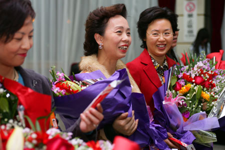 CPPCC members hold bouquets of flowers presented to them as gifts on Thursday to celebrate International Women's Day, which falls on Saturday. [China Daily]
