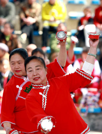 Two women from Yi ethnic minority perform a folk dance to celebrate the 98th anniversary of International Women's Day, which falls an Saturday, in Southwest China's Yunnan Province on March 6, 2008. A total of 400 middle-aged women took part in the event. [Xinhua]