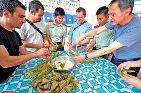 British engineers learn how to make rice dumplings with police in Taizhou, Zhejiang province, on Wednesday. The police introduced the foreigners to customs of the Dragon Boat Festival before their return to the UK.