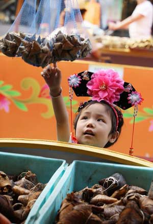A girl points at rice dumplings hung at a street stall in Shanghai June 4, 2008. The Dragon Boat Festival falls on June 8 this year. As a tradition, people eat rice dumplings with meat, peanut, egg yolk, or other fillings wrapped in bamboo leaves during the festival.