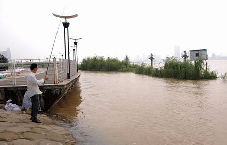 Workers begin shoring up breached river dikes in E China