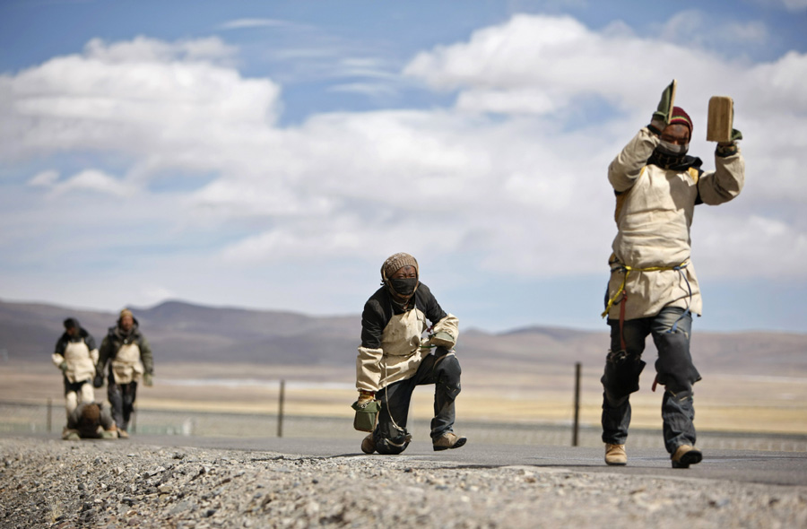 Tibetan pilgrims kowtow along a road