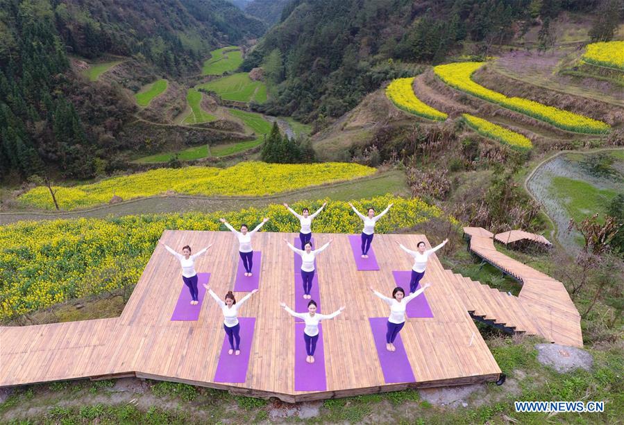 Yoga fans practise yoga on farmland of flowers in C China's Zhangjiajie<BR>