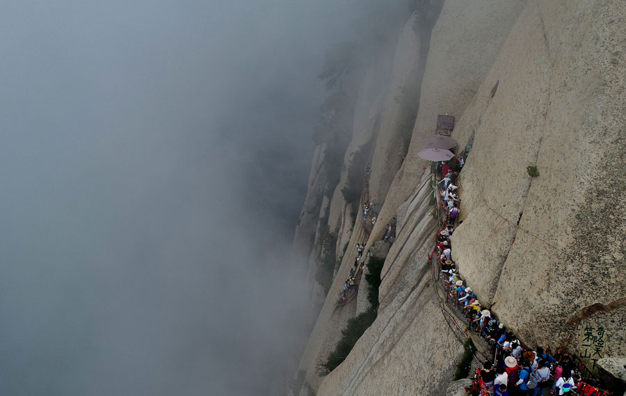 Tourists walk on plank road built on cliff at Huashan Mountain