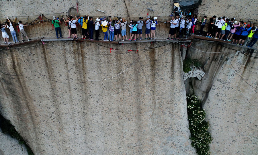 Tourists walk on plank road built on cliff at Huashan Mountain