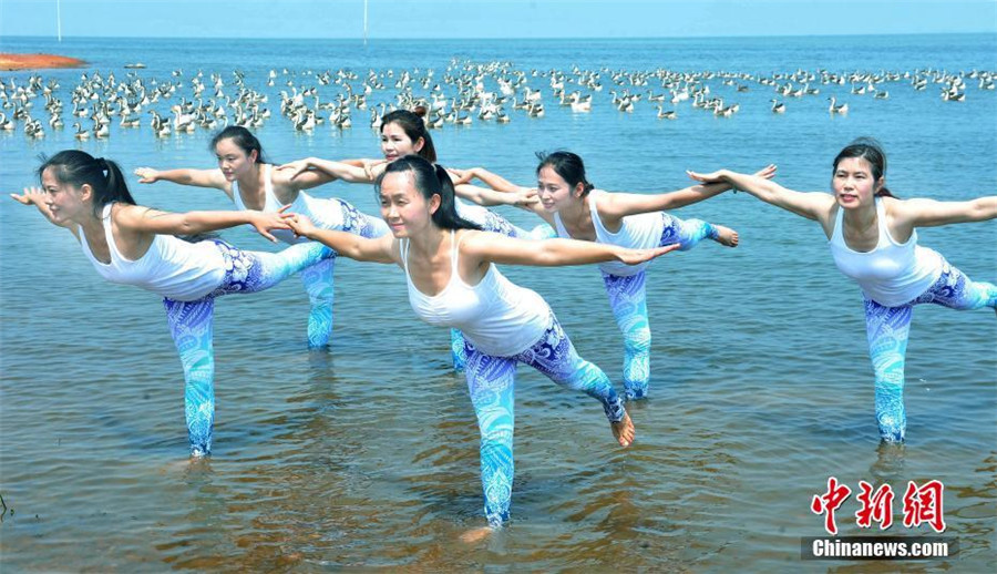 Yoga lovers stretch next to Poyang Lake