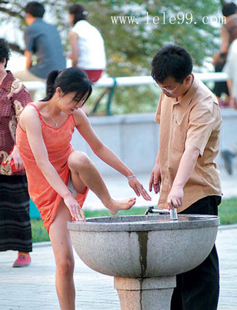A woman is about to wash her foot in a public stone basin
