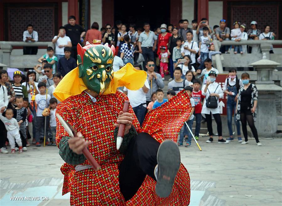 Tourists view Nuo dance at China's Yongcheng