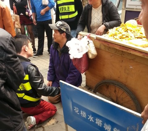 武汉摊贩因车辆被扣下跪求情 城管与其“对跪”
