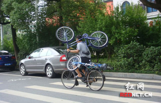 单手骑自行车搭载两车 大力士马路上杂耍(