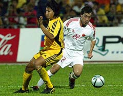 Chinese player Yan Song (R) fights for the ball with a Malaysian player (L) during their 2006 World Cup qualifier on Septermber 8, 2004.