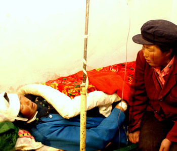 Zhang Aiqiao, a 20-year-old resident of Baozi Village, Minxian County in Northwest China's Gansu Province, takes care of her injured mother. An earthquake, measuring 5.2 degrees on the Richter scale, struck Minxian County, Nonvember 2003. [newsphoto/file]