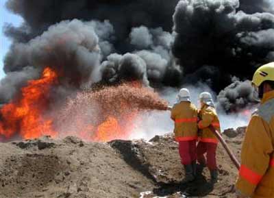 Firefighters try to contain an oil pipeline fire after an attack by insurgents near Beiji, 250 kilometers (155 miles) north of Baghdad, Iraq, Tuesday Sept. 14, 2004. Saboteurs blew up a junction where multiple oil pipelines cross the Tigris River in northern Iraq on Tuesday, setting off a chain reaction in power generation systems that left the entire country without power. [AP] 