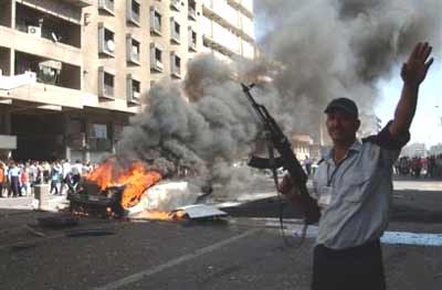 An Iraqi policeman keeps the crowd of people out after a car bomb explosion in central Baghdad, Iraq, Tuesday Sept. 14, 2004. A suicide bomber detonated an explosive, killing himself and injuring one pedestrian. [AP Photo]