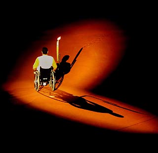 A Greek Paralympian carries the Olympic Flame into the Athens Olympic stadium during the opening ceremony of the Athens 2004 Paralympic Games September 17, 2004. A total of 3,837 athletes, representing a record number of 136 nations, paraded in the crowded stadium. [Reuters]