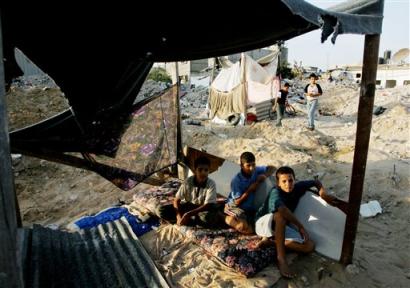 Palestinian youths sit in a makeshift tent at the site of their destroyed family house in the Jebaliya refugee camp, northern Gaza Strip, Saturday, Oct. 16, 2004.[AP] 