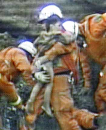 A two-year-old boy, Yuta Minagawa, is rescued from a buried car, seen in this image taken from JNN/TBS television, in an earthquake-triggered landslide in Nagaoka, northern Japan October 27, 2004. A woman and two small children who were trapped for nearly four days were found on Wednesday and media said all three were alive. [Reuters]